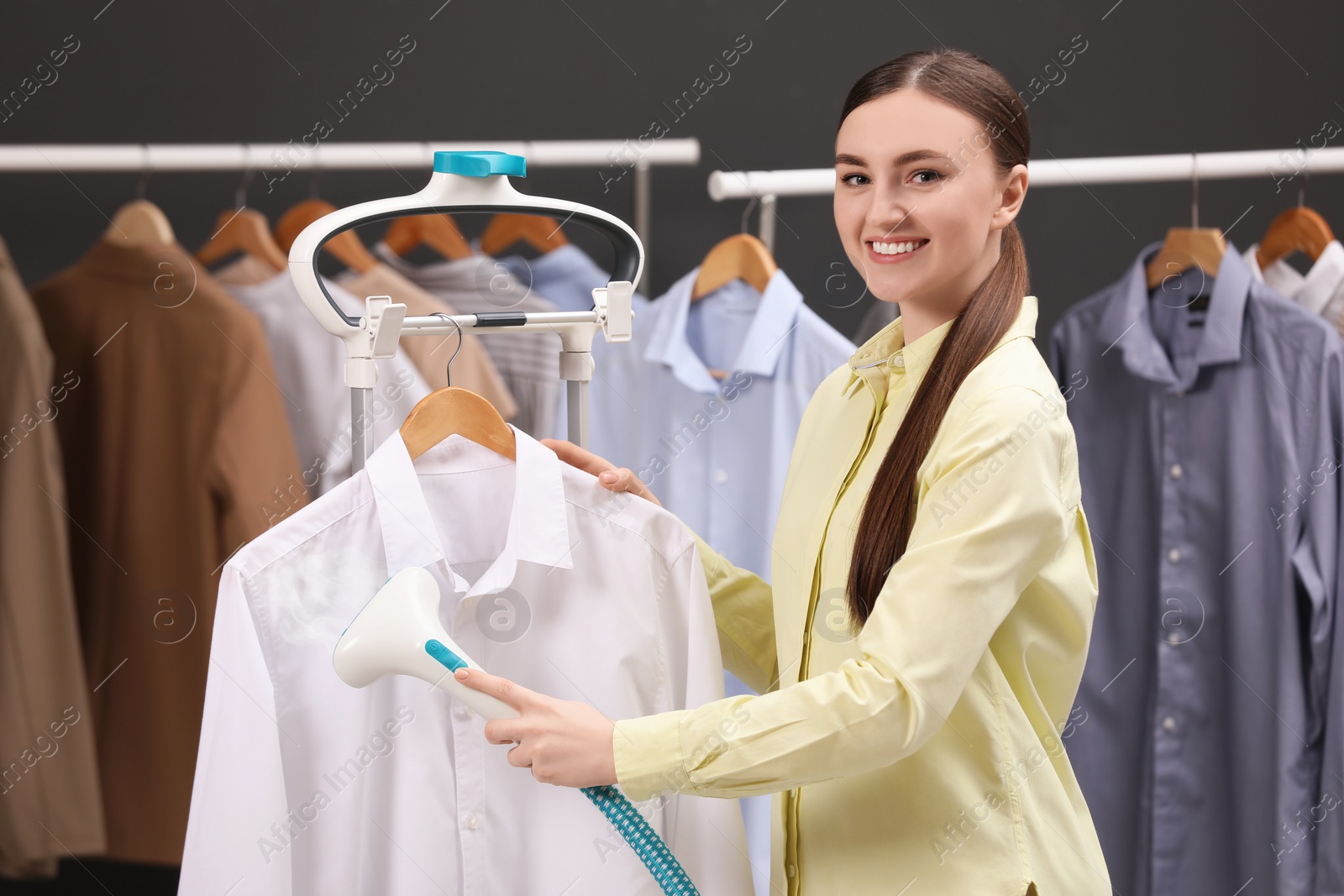 Photo of Woman steaming shirt on hanger in room