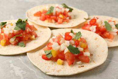 Photo of Delicious tacos with vegetables and parsley on grey marble table, closeup