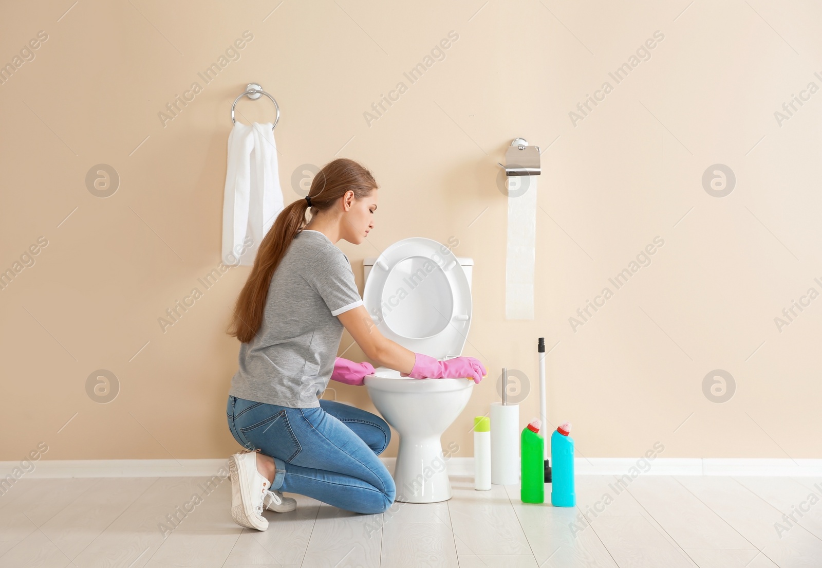 Photo of Woman cleaning toilet bowl in bathroom