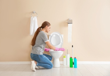 Woman cleaning toilet bowl in bathroom