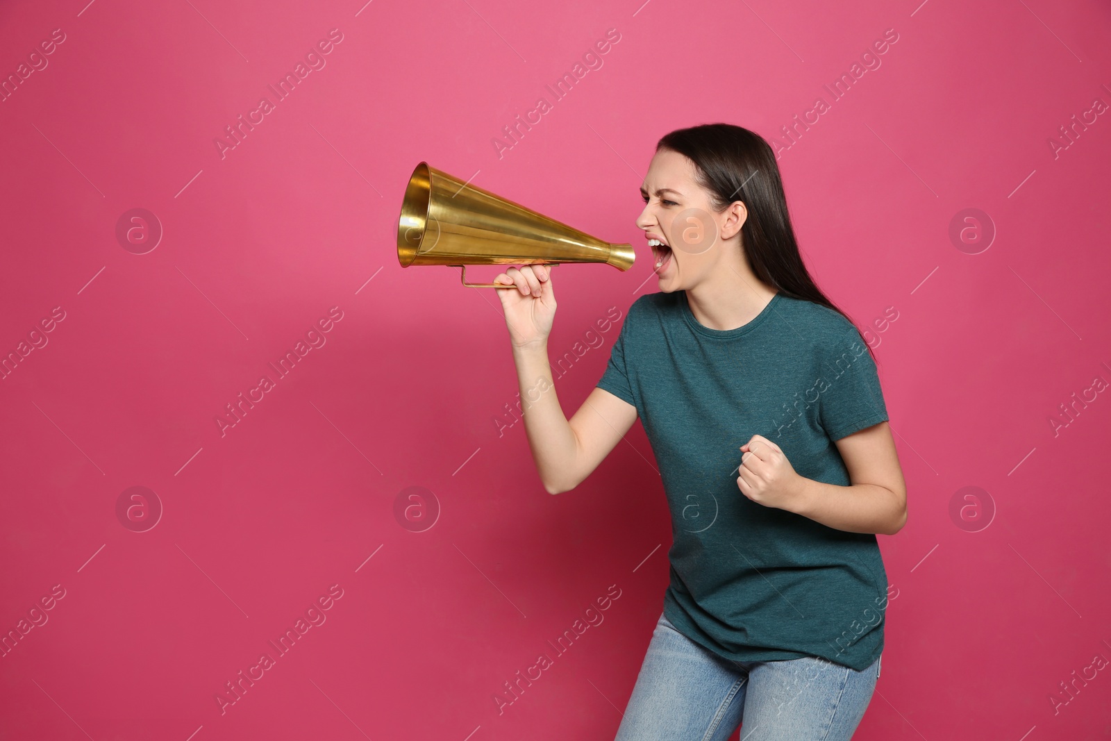 Photo of Emotional young woman with megaphone on color background