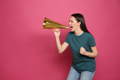 Emotional young woman with megaphone on color background