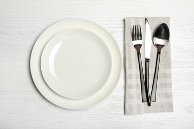 Plates and cutlery on wooden table, top view. New setting