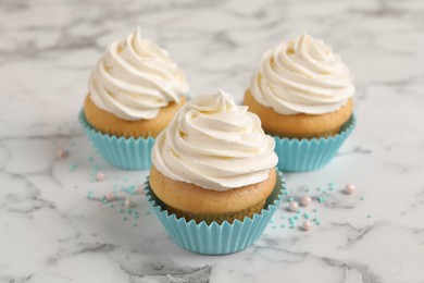 Delicious cupcakes decorated with cream on white marble table