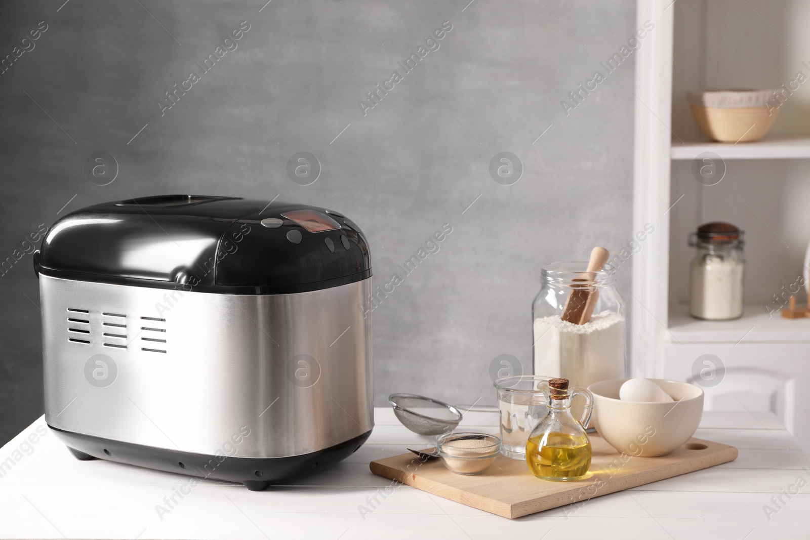 Photo of Breadmaker and different products on white wooden table indoors