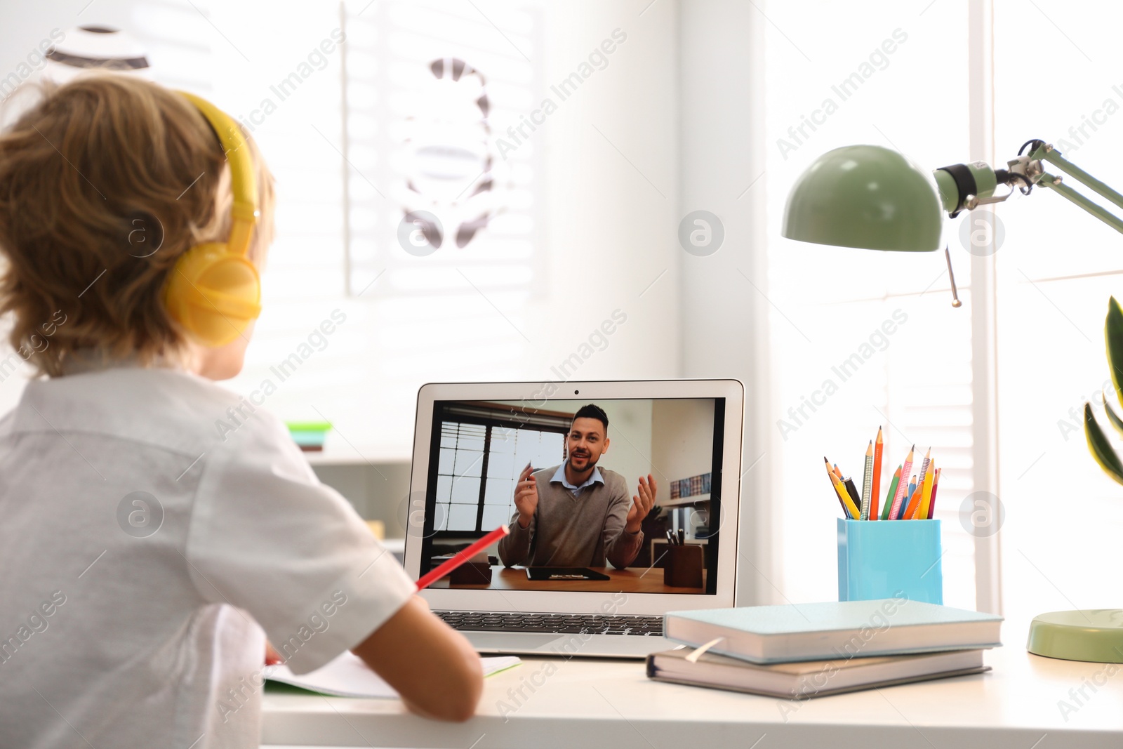 Photo of Little boy studying with teacher via video conference at home. Distance learning during COVID-19 pandemic