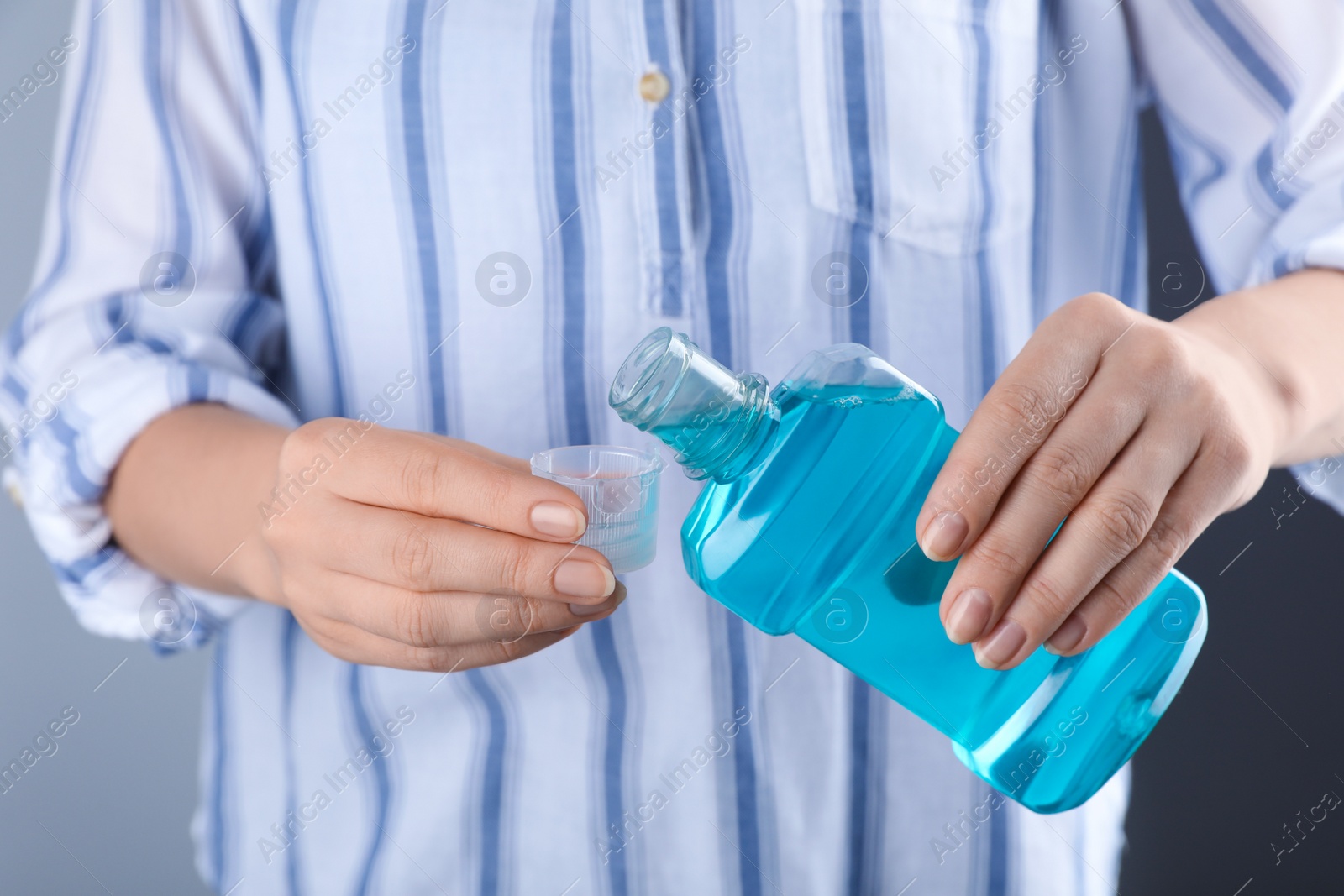 Photo of Woman pouring mouthwash from bottle into lid, closeup