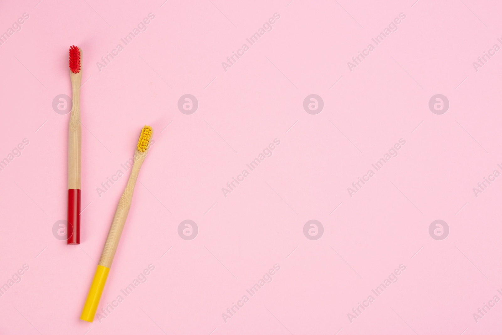 Photo of Toothbrushes made of bamboo on pink background, flat lay. Space for text