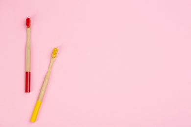 Toothbrushes made of bamboo on pink background, flat lay. Space for text