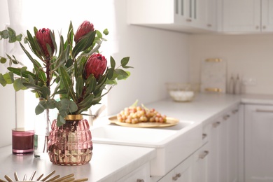 Beautiful protea flowers on countertop in kitchen, space for text. Interior design