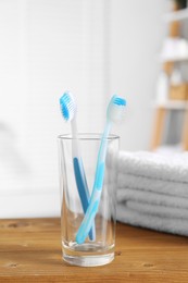 Photo of Plastic toothbrushes and towels on wooden table in bathroom