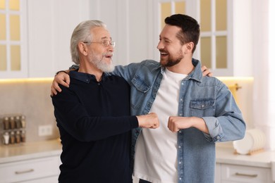 Photo of Happy son and his dad making fist bump at home