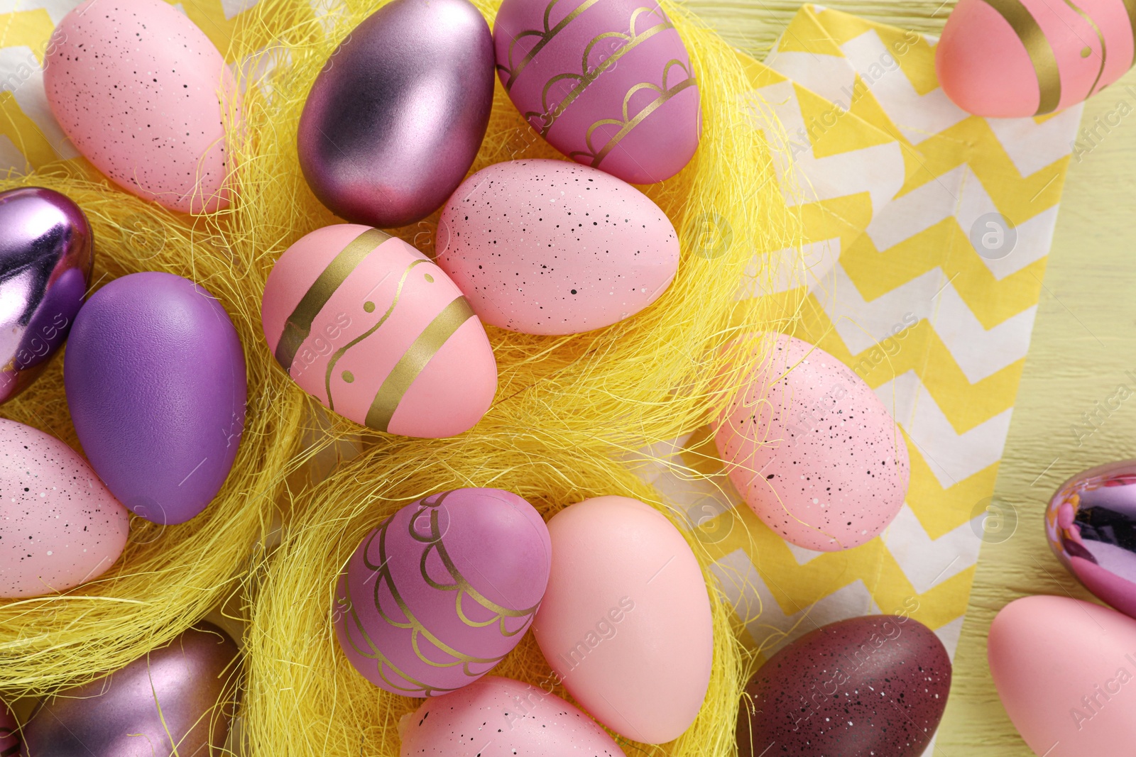 Photo of Decorative nests with many beautiful Easter eggs on table, flat lay