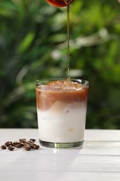 Photo of Making iced coffee at white wooden table outdoors, closeup