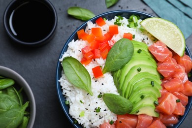 Photo of Delicious poke bowl with salmon, spinach and avocado served on black table, flat lay