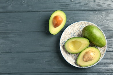 Photo of Plate with ripe avocados on wooden background, top view