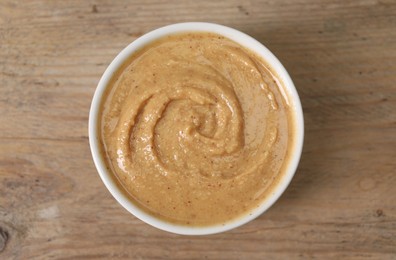 Photo of Delicious nut butter in bowl on wooden table, top view