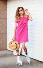 Happy young woman with retro roller skates near white garage door