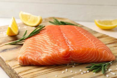 Photo of Fresh salmon fillet with rosemary and salt on wooden board, closeup