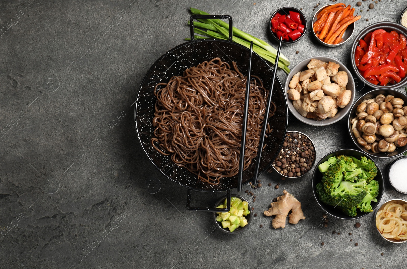 Photo of Wok with noodles, chicken and other products on grey table, flat lay. Space for text