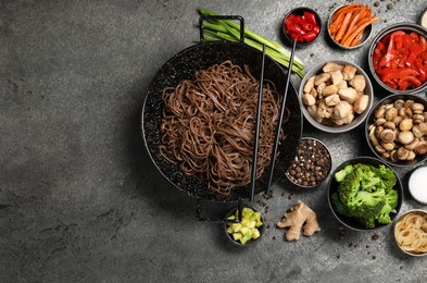 Photo of Wok with noodles, chicken and other products on grey table, flat lay. Space for text