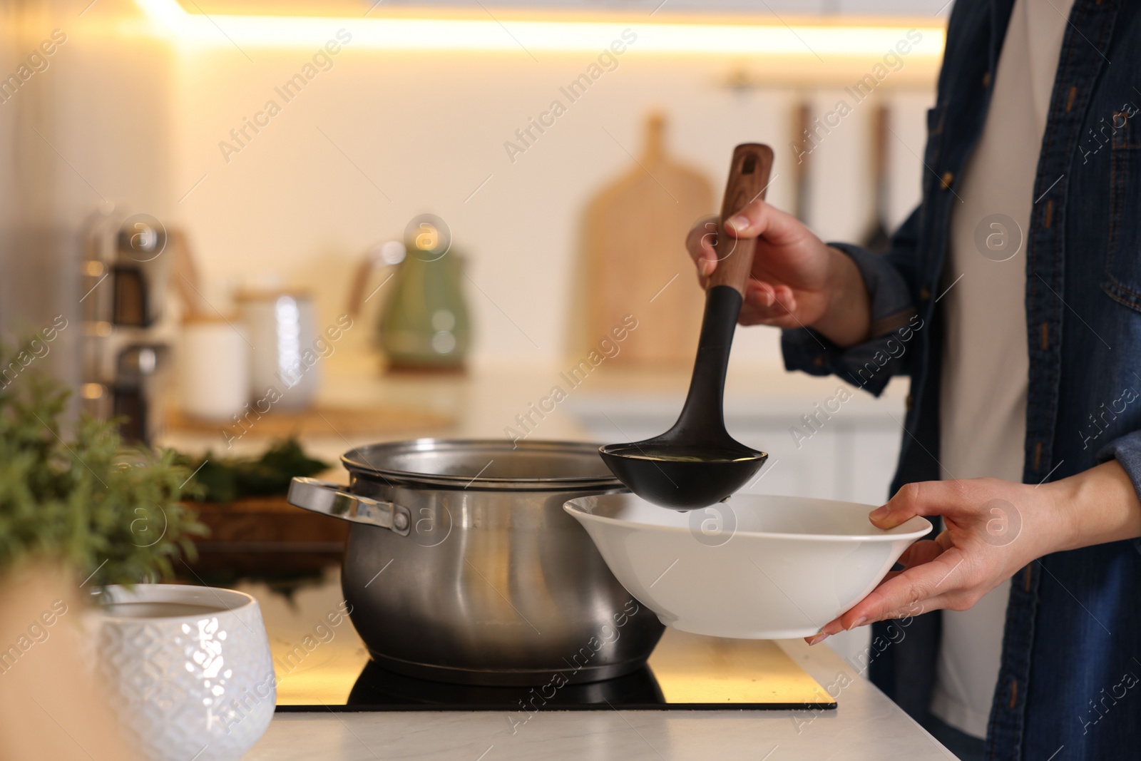 Photo of Woman pouring tasty soup into bowl at countertop in kitchen, closeup