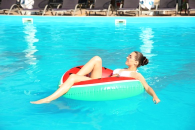 Beautiful young woman wearing bikini on inflatable ring in swimming pool