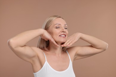 Beautiful woman touching her neck on beige background