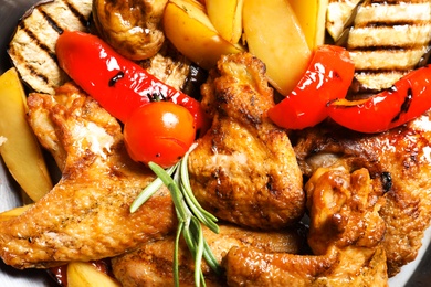 Delicious barbecued chicken wings with garnish served in wok, closeup