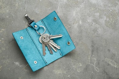 Photo of Stylish leather holder with keys on grey textured table, top view. Space for text