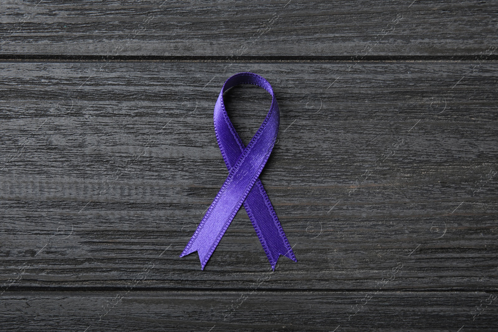 Photo of Purple ribbon on grey wooden background, top view. Domestic violence awareness