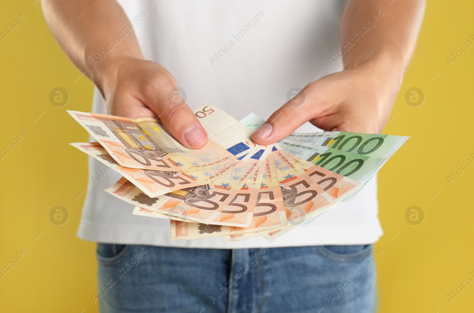 Photo of Man with Euro banknotes on yellow background, closeup