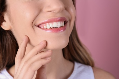 Young woman with healthy teeth and beautiful smile on color background, closeup