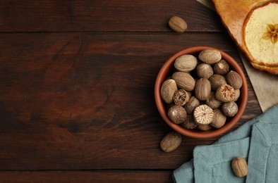 Photo of Nutmeg seeds and tasty apple pie on wooden table, flat lay. Space for text