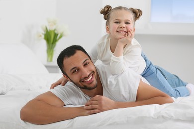 Little girl with her father on bed at home. International family