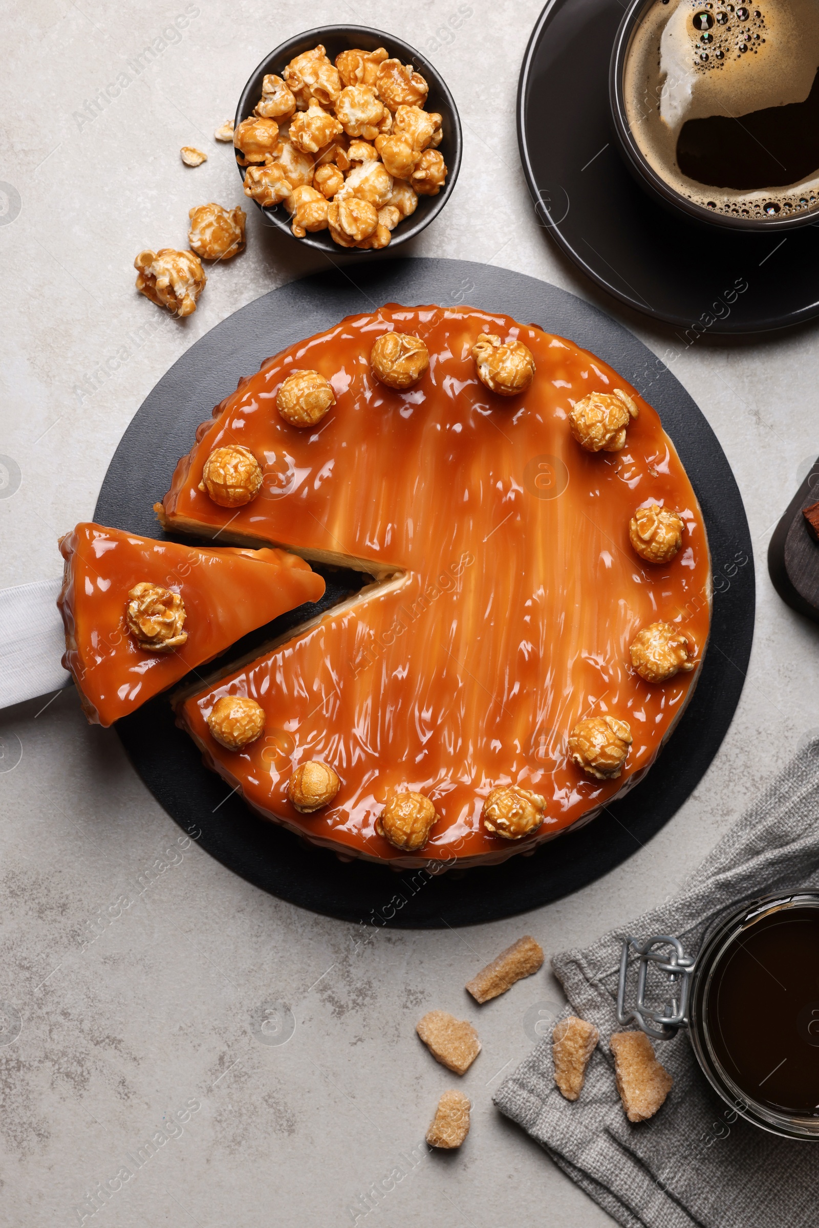 Photo of Sliced delicious caramel cheesecake with popcorn served on light grey table, flat lay