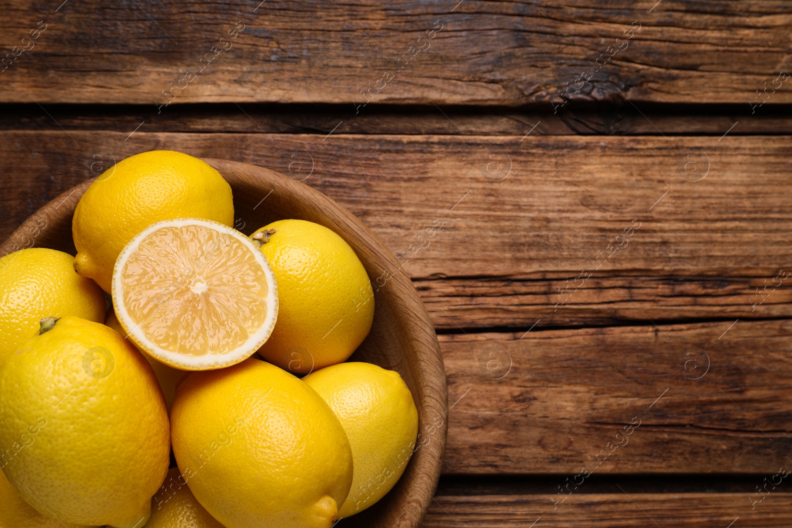 Photo of Many fresh ripe lemons on wooden table, top view. Space for text
