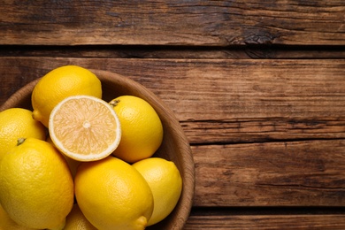 Many fresh ripe lemons on wooden table, top view. Space for text