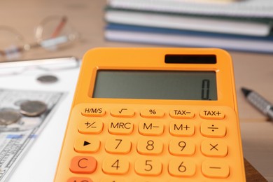 Photo of Orange calculator on table, closeup. Retirement concept