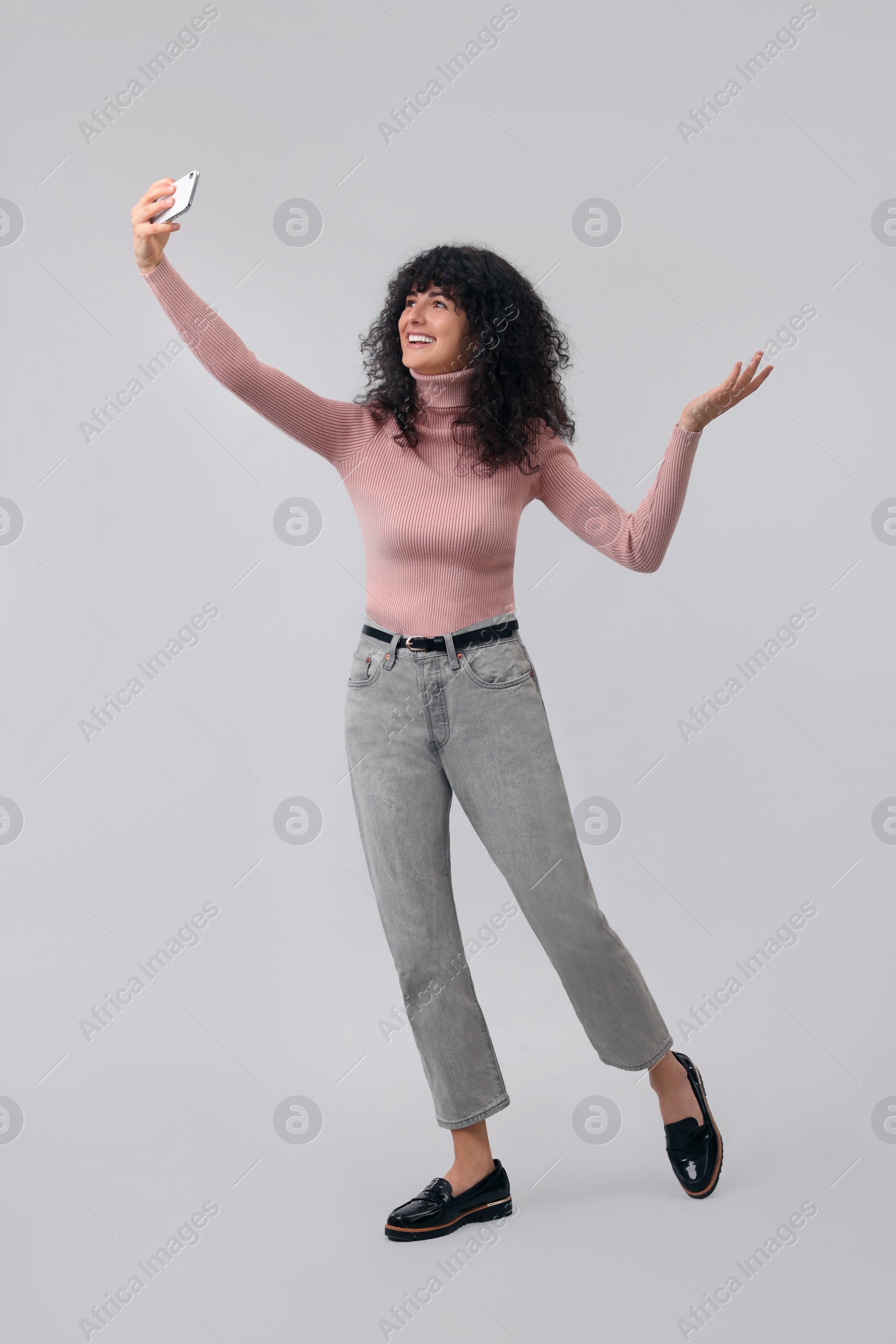 Photo of Beautiful young woman taking selfie on light grey background