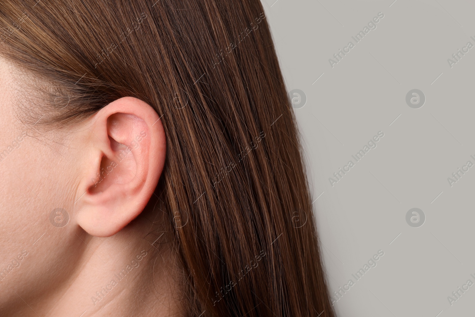 Photo of Closeup view of woman against light grey background, focus on ear