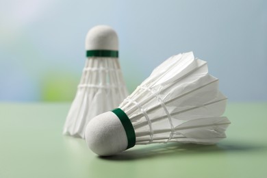 Feather badminton shuttlecocks on green table against blurred background, closeup