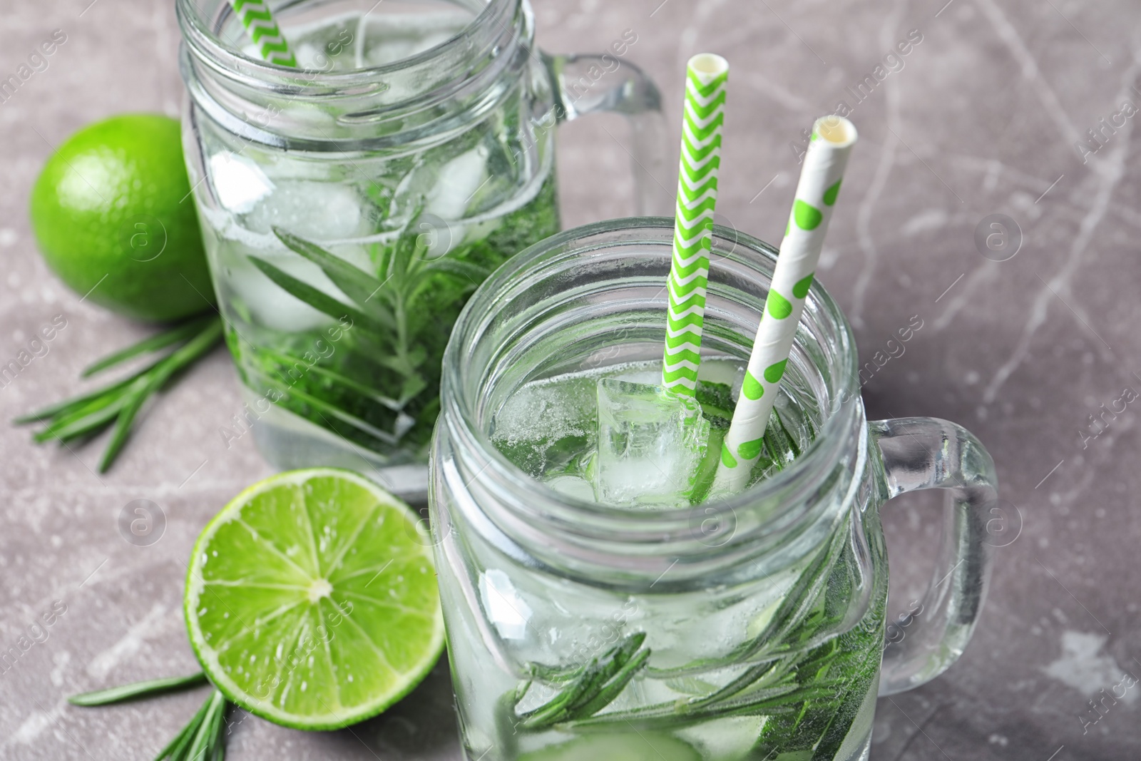 Photo of Natural lemonade with cucumber, lime and rosemary in mason jars on table, closeup