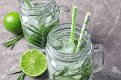 Photo of Natural lemonade with cucumber, lime and rosemary in mason jars on table, closeup