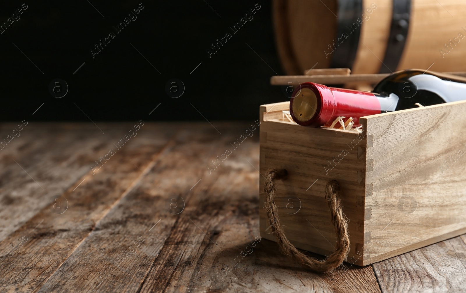 Photo of Crate with bottle of wine on wooden table. Space for text