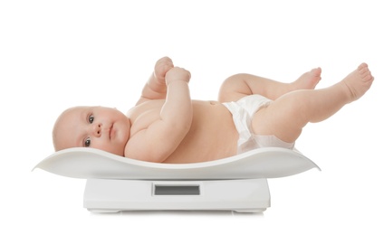 Photo of Cute little baby lying on scales against white background