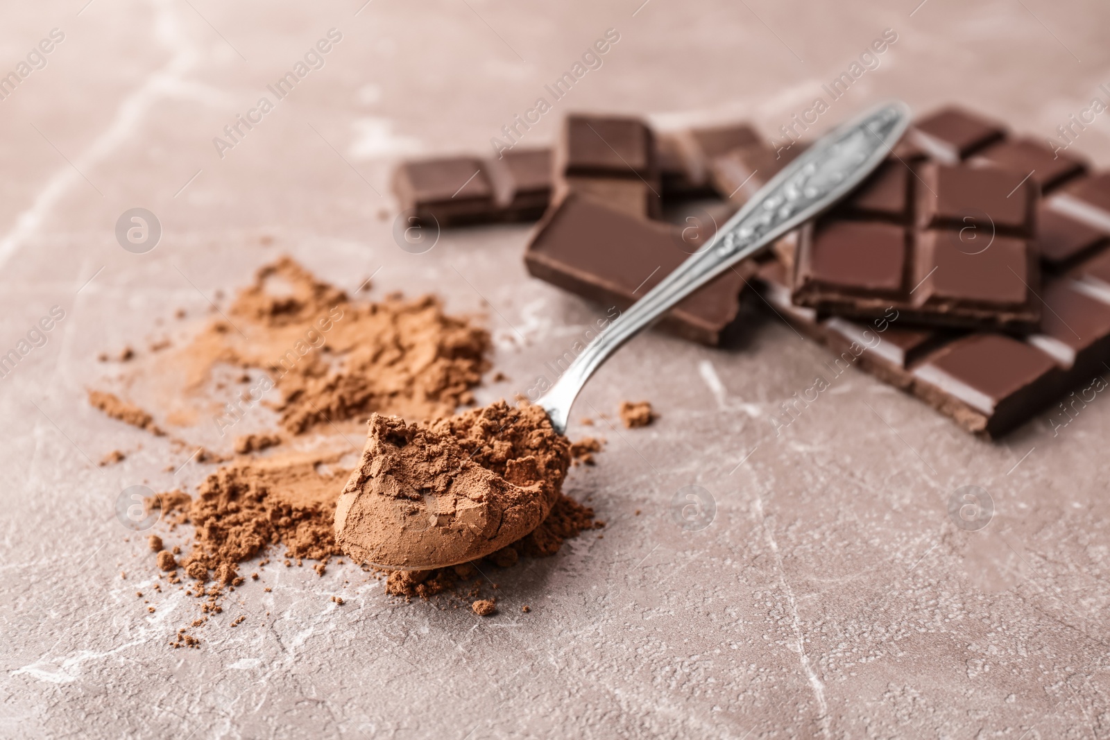 Photo of Spoon with cocoa powder and tasty chocolate on table