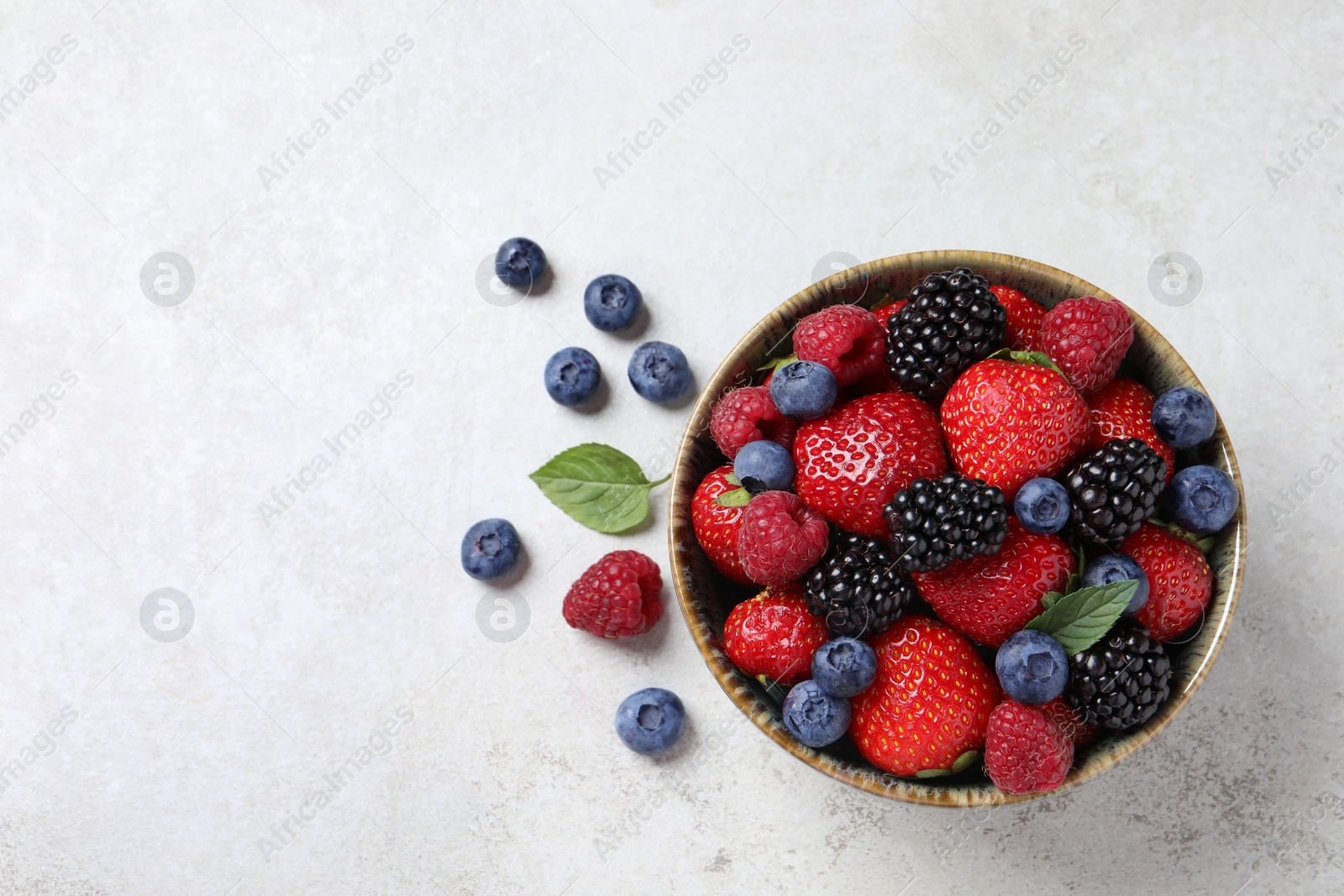 Photo of Different fresh ripe berries on light grey table, flat lay. Space for text