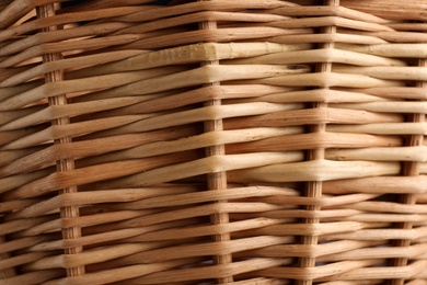 Handmade wicker basket made of natural material as background, closeup view