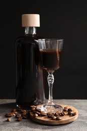 Bottle of coffee liqueur, shot glass and beans on light grey table